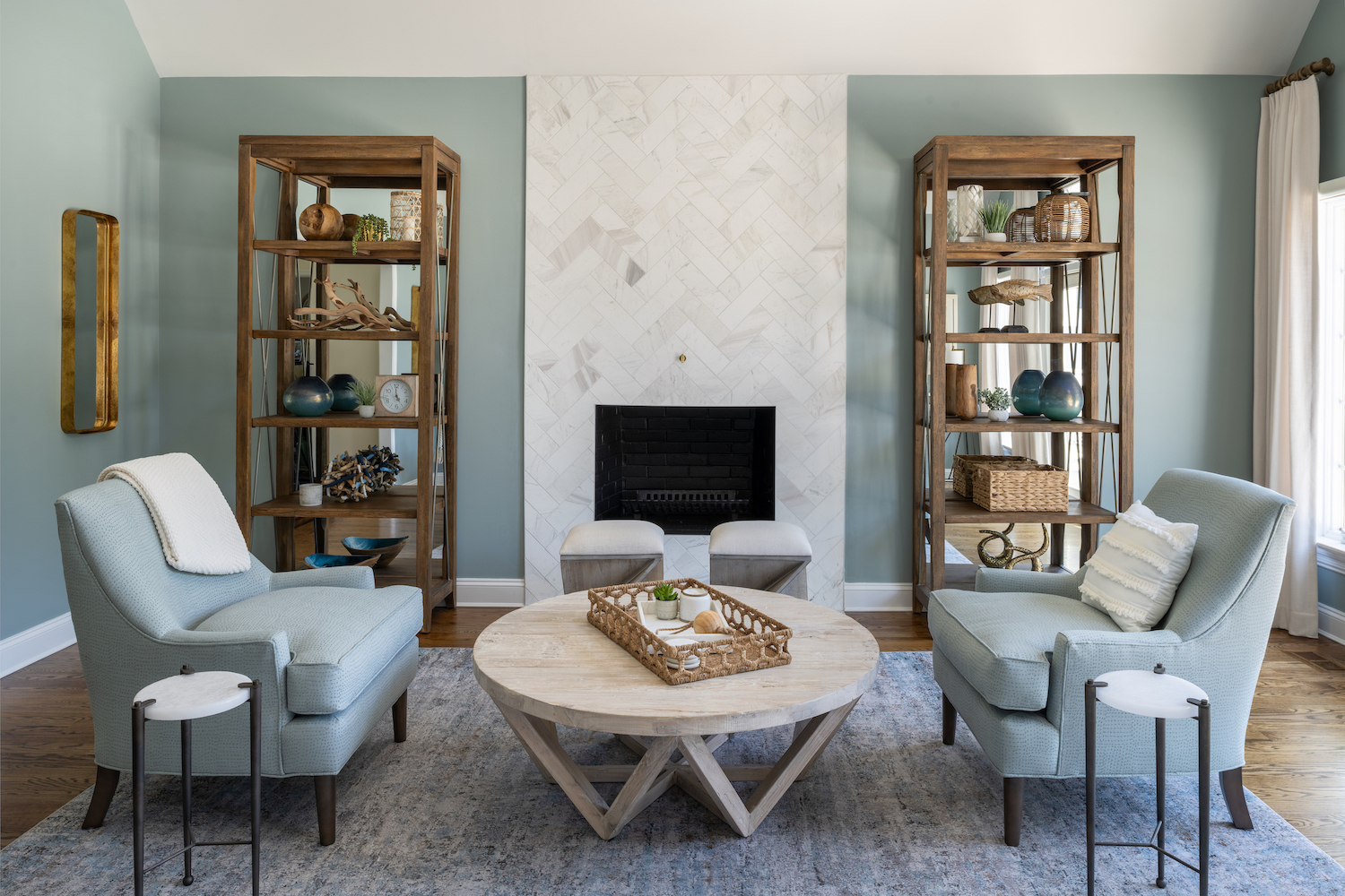 Adding personality to your home. Living room filled with personality. Two etagere book shelves filled with treasured items flank a tall herringbone marble fireplace.